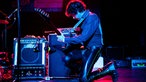 Gitarrist überprüft kniend beim Spielen zeitgleich den Sound aus der Box 