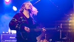 Der Bassist von "The Temper Trap" steht auf der Bühne und spielt