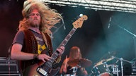 Der Bassist der Band ist am rocken und schwingt seine langen Haare umher