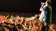 Sänger der Beatsteaks singt am Rande der Bühne und lässt sich vom Publikum feiern