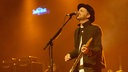 Fran Healy von Travis spielt auf der Bühne Gitarre und singt ins Mikrofon