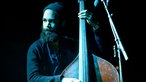 Eines der Bandmitglieder steht an einem großen Contrabass.