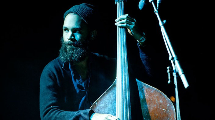 Eines der Bandmitglieder steht an einem großen Contrabass.