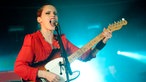 Anna Calvi steht mit ihrer Gitarre auf der Bühne und singt mit aufgerissenem Mund in ihr Mikrofon.
