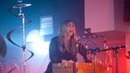 Ein Bandmitglied von Anna Calvi steht im Hintergrund.