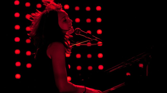 Sophie Hunger mit zurückgewehten Haaren beim Singen am Klavier