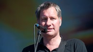 Sänger der Band Kettcar singt ins Mikrofon und blickt zur Seite