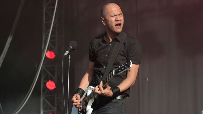 Danko Jones schaut zu seinen Bandkollegen rüber während er auf seiner weißen Gitarre spielt