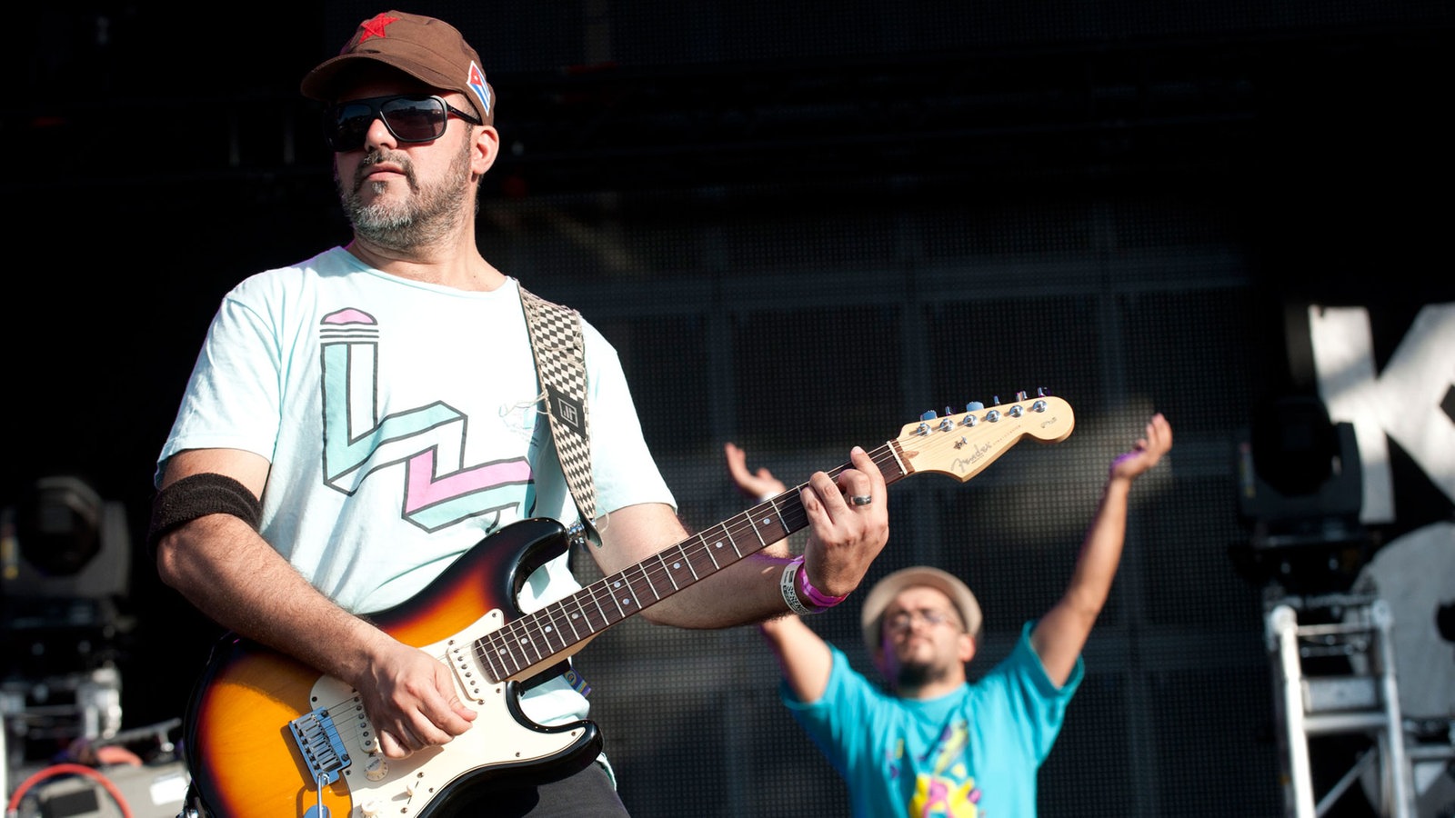 Gitarrenspieler im Vordergrund, klatschendes Bandmitglied im Hintergrund