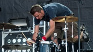 Drummer spielt nach vorne gebeugt und im Stehen