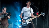 Kameramann steht hinter dem Bassisten und filmt ihn
