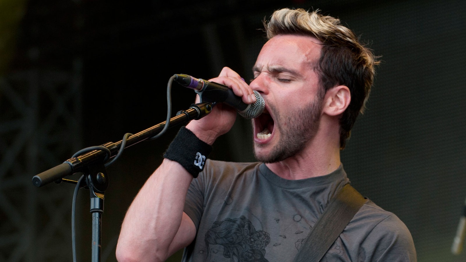 Der Frontmann singt ins Mikro, er hat blondgefärbte haare