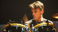 Der Drummer der Band sieht angestrengt nach unten.