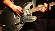 Nahaufnahme einer matt schwarzen Semi-Akustik Gitarre