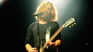Der Frontmann der Band steht in einem hellen Licht am Mikrofon.
