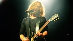 Der Frontmann der Band steht in einem hellen Licht am Mikrofon.