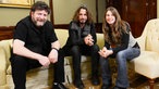 Der Sänger und der Bassist sitzen gemeinsam mit Conny Schiffbauer beim Interview auf einer Couch.