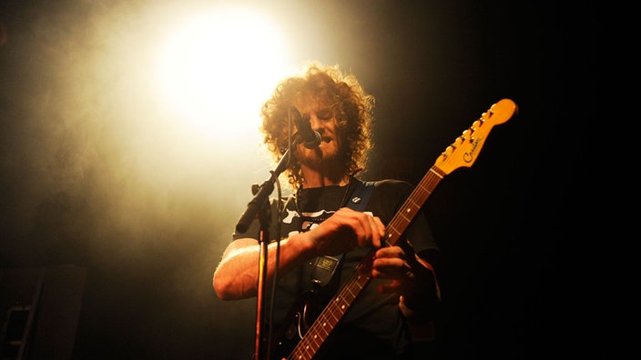 State Radio's Sänger verändert etwas an seiner Gitarre