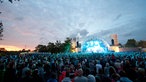 Die hell ausgeleuchtete Bühne des Summerjam wird von einer Menschenmasse belagert die das ganze Bild einnimmt