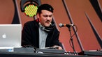 Der DJ raucht während er seine Plattenspieler einstellt