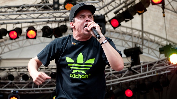 Der Rapper trägt ein T-Shirt mit Hanfblatt während er rappt