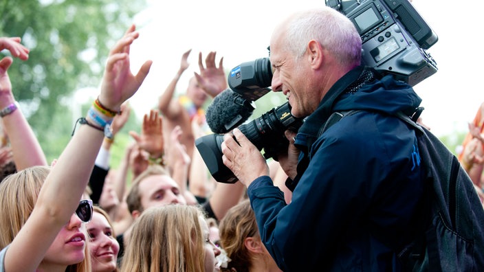 Ein Kameramann filmt die Besucher des Festivals während sie vor der Bühne stehen