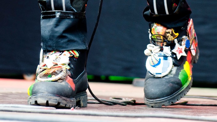 Die Jamaikaner tragen hübsch verzierte4 Schuhe in den Farben ihres Landes. Mehrere Anhänger und Ketten sind zusätzlich an der Aussenseite angebracht