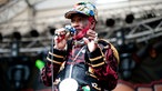 Lee "Scratch" Perry blickt von der Bühne, um den Hals eine grosse schwere Kette, ähnlich der Uhr von Jam Master Jay (Run DMC)