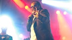 "Madcon"-Mitglied Yosef Wolde-Mariam formt einen Hasen mit der linken Hand. Er lächelt in die Kamera und trägt eine Sonnenbrille