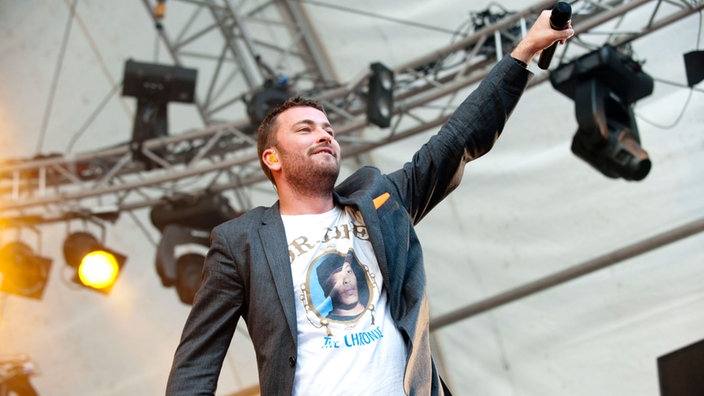 Kiffer Marteria hält das Mikrofon in die Luft als möchte er die Stimmen des Publikums aufnehmen