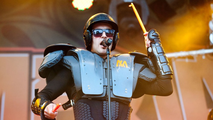 Marterias Show wird von mehreren maskiereten Sängern begleitet. Hier ein Mann der eine Robo-Cop ähnliche Panzerung trägt. Er hat eine Sonnenbrille auf