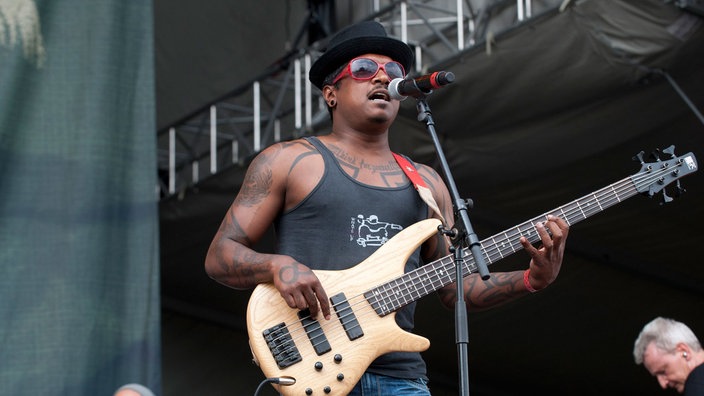 Bassist mit roter Brille und Hut am Mikrofon
