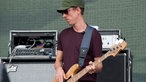 Bassist mit grüner Kappe und Sonnenbrille schaut zur Seite