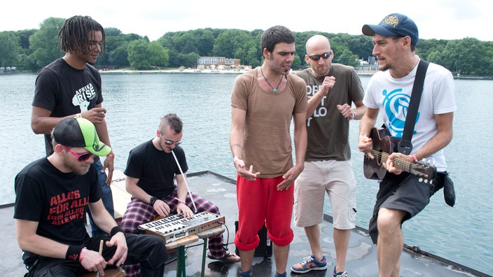 Eine Band spielt mit Akustikinstrumenten am Seeufer