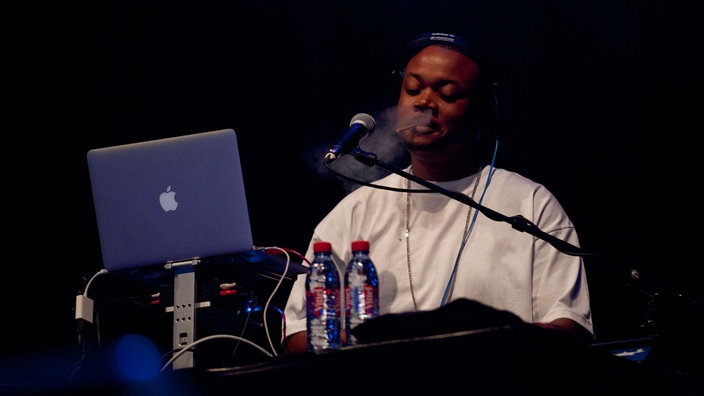 Mann am Synthesizer mit Macbook
