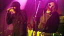 Sänger und Gitarrist auf der Bühne, der Gitarrist hat eine weiße Sonnenbrille auf