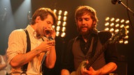 Links Greg Hommert an der Mundharmonika und rechts der Giatrrist Dylan Fitch