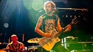 Der Sänger und Gitarrist der Band steht am Mikrofon im Hintergrund sieht man den Schlagzeuger