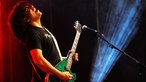The I.M.F´s Bandmitglied guckt hoch und spielt auf grüner Glitzergitarre