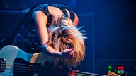 Charlotte Copper beugt sich nach vorn über ihren Bass