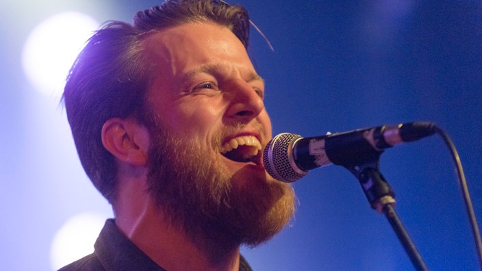Sänger von Tim Vantol singt fröhlich ins Mikrofon