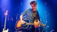 Sänger und Gitarrist von Tim Vantol spielt ein heißes Solo auf seiner Akustikgitarre in Orange Sunburst Lackierung