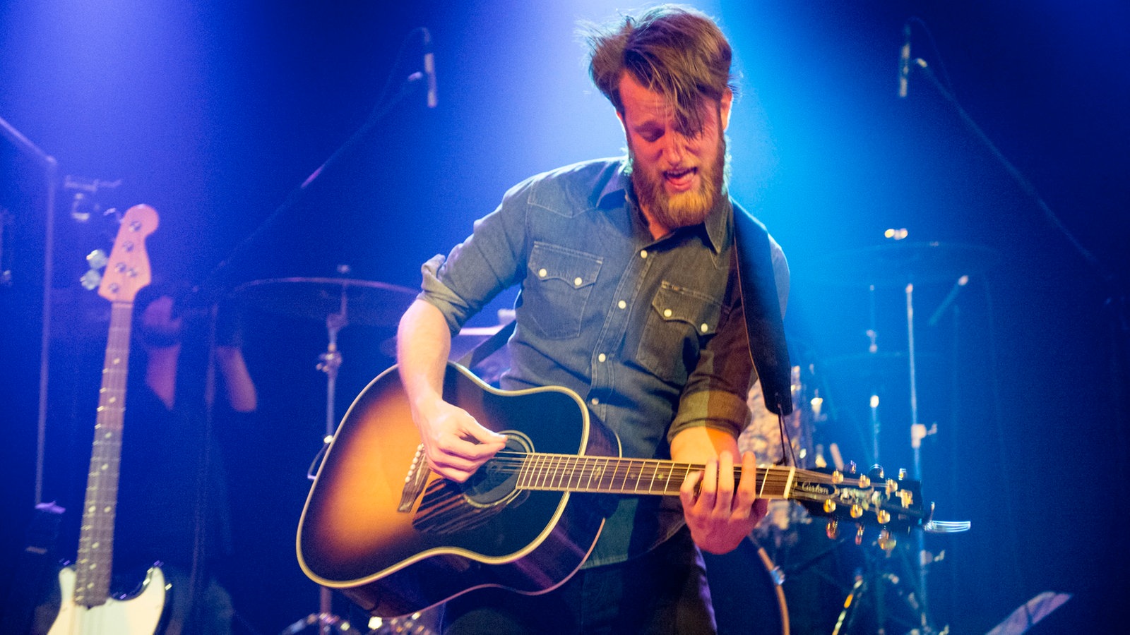 Sänger und Gitarrist von Tim Vantol spielt ein heißes Solo auf seiner Akustikgitarre in Orange Sunburst Lackierung
