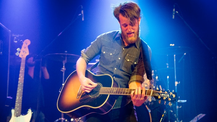 Sänger und Gitarrist von Tim Vantol spielt ein heißes Solo auf seiner Akustikgitarre in Orange Sunburst Lackierung