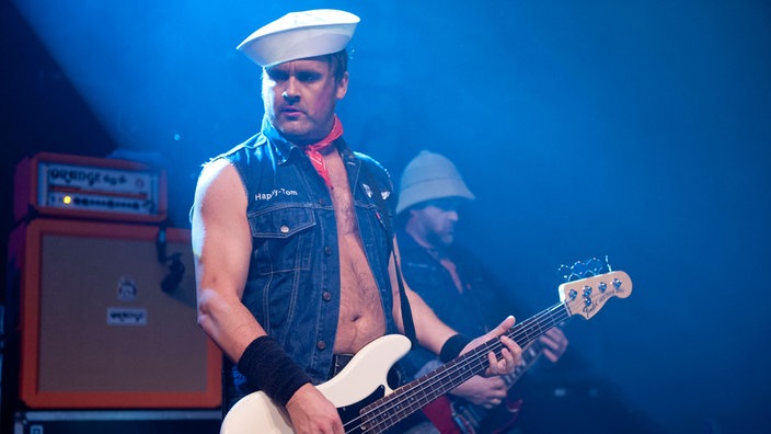 Der Bassist sieht zur Seite während er auf seinem instrument spielt.