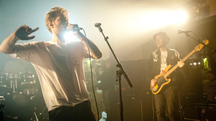 Der Frontman in wilder Geste, seitlich dahinter und deutlich verhaltener, der Bassist.