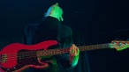 Mann mit  roter Gitarre guckt hoch beim spielen
