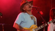 Dickey Betts singt und wird von roten Scheinwerfern angestrahlt
