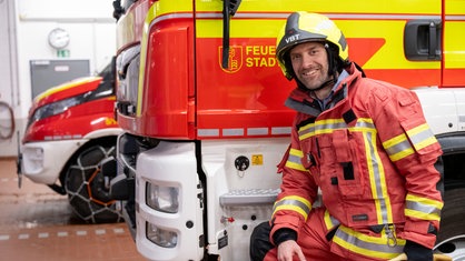 Daniel Aßmann in der Mitte zwischen zwei Feuerwehrpersonen.