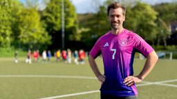 Das Bild zeigt Daniel Aßmann auf einem Fussballplatz. Er trägt das Auswärtstrikot der deutschen Nationalmannschaft für die diesjährige EM.